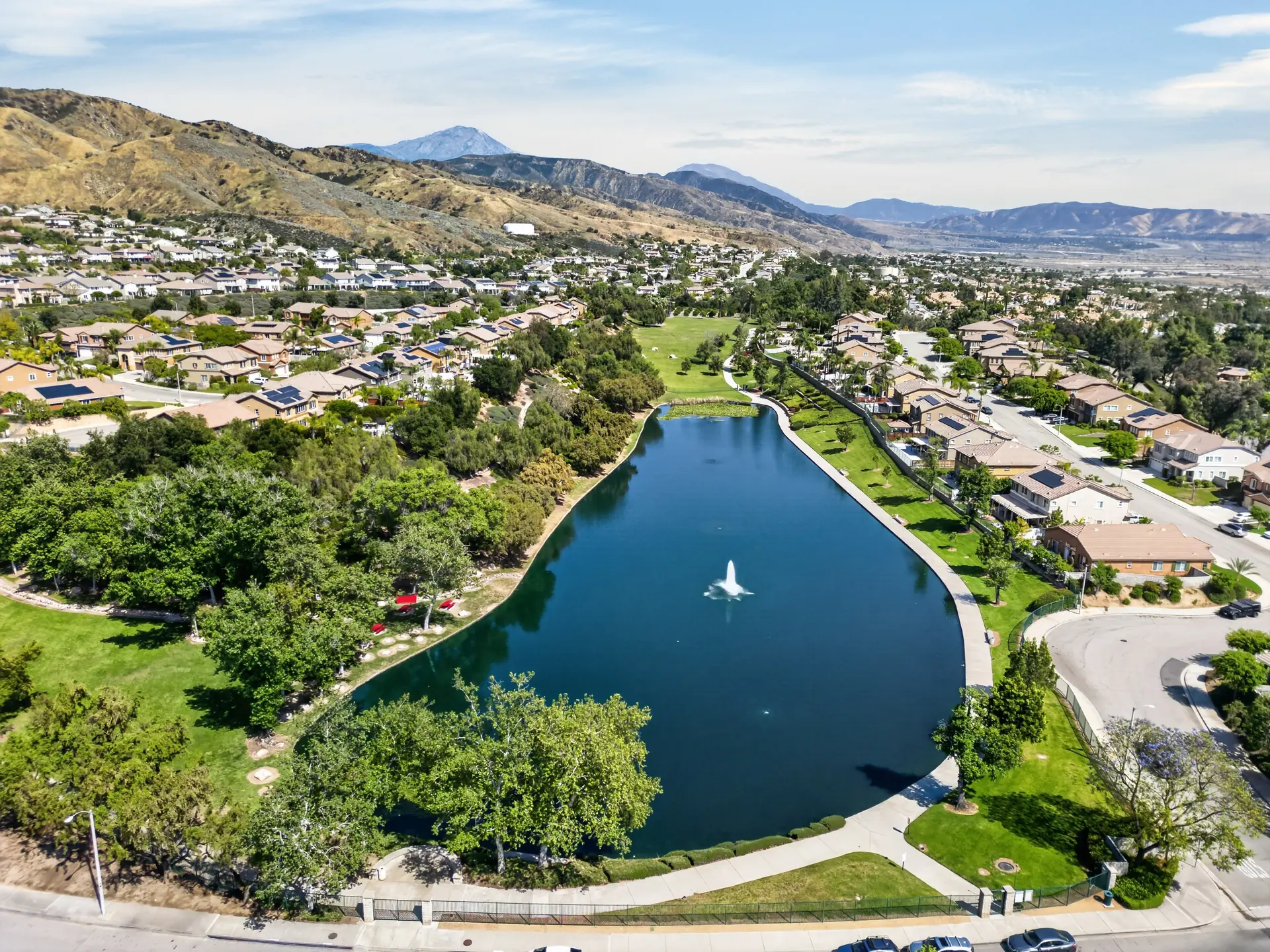 Aerial drone photo of community lake with fountain and mountain backdrop